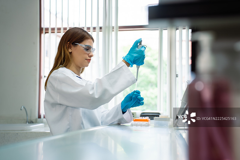 中年女性科学家在实验室使用微量移液器图片素材