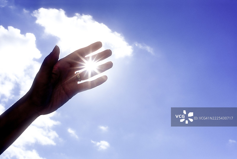 阳光透过女人的手指洒在天空上图片素材