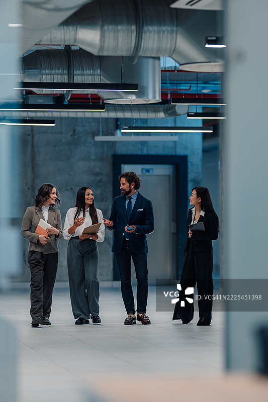 商务人士在办公大楼内边走边讨论图片素材