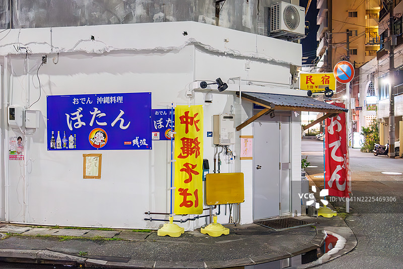 日本风格酒馆的外观。开放式露台柜台和旧摩托车的展示。游客们走进店里。偶尔有出租车经过。图片素材