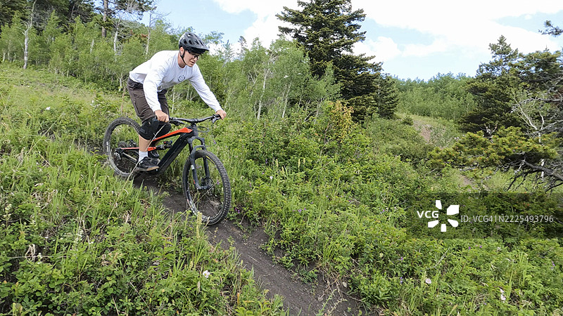 年轻男子在小径上骑山地自行车越过岩石图片素材