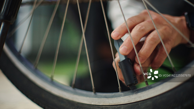 成熟的女性在给自行车轮胎充气。图片素材