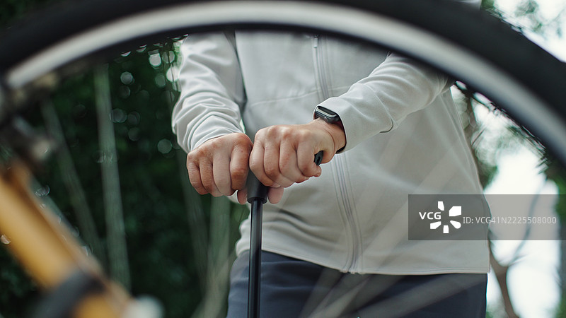 成熟的女性在给自行车轮胎充气。图片素材