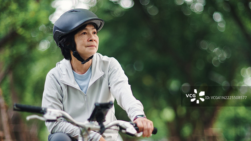 成熟的女性在骑行休息时欣赏美丽的自然风光。图片素材