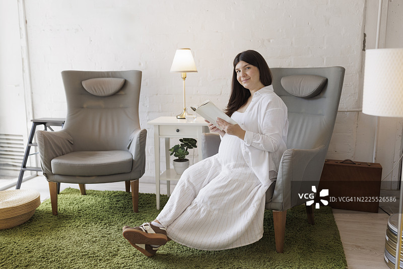怀孕的年轻女性在阅读一本书。图片素材