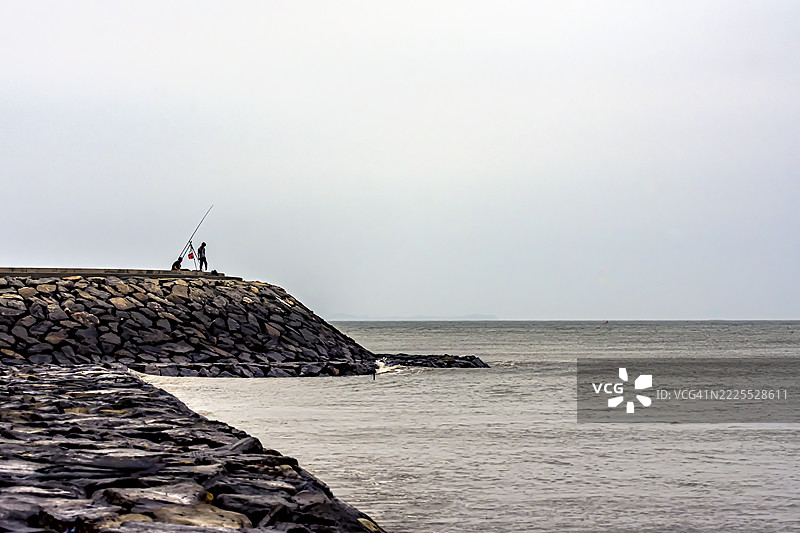 在岩石码头钓鱼的两个人图片素材