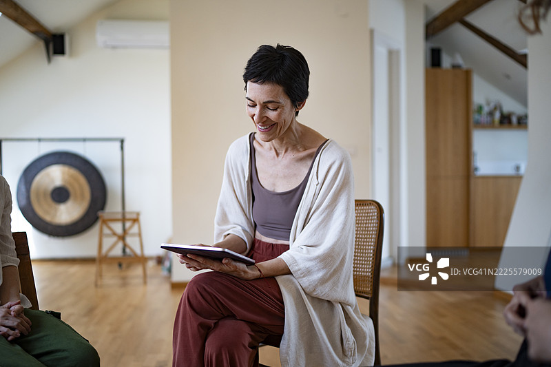 微笑的瑜伽老师在上课前查看平板上的笔记图片素材