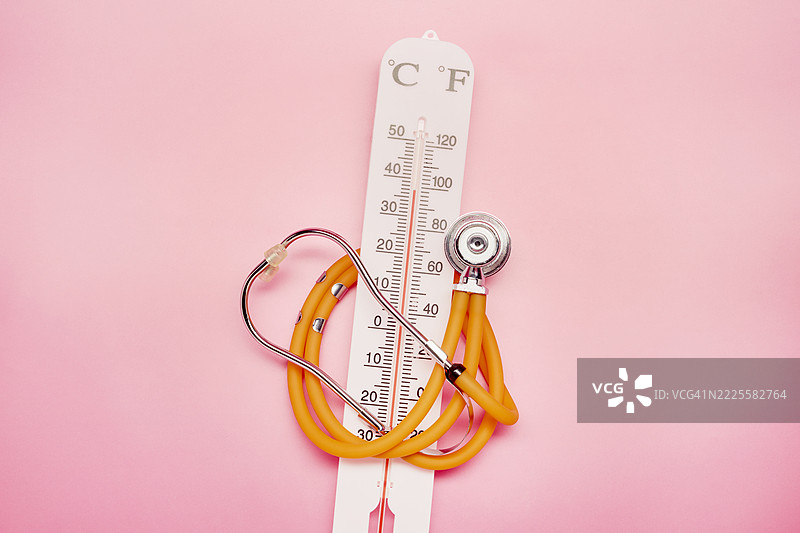 粉色背景上的温度计和听诊器图片素材