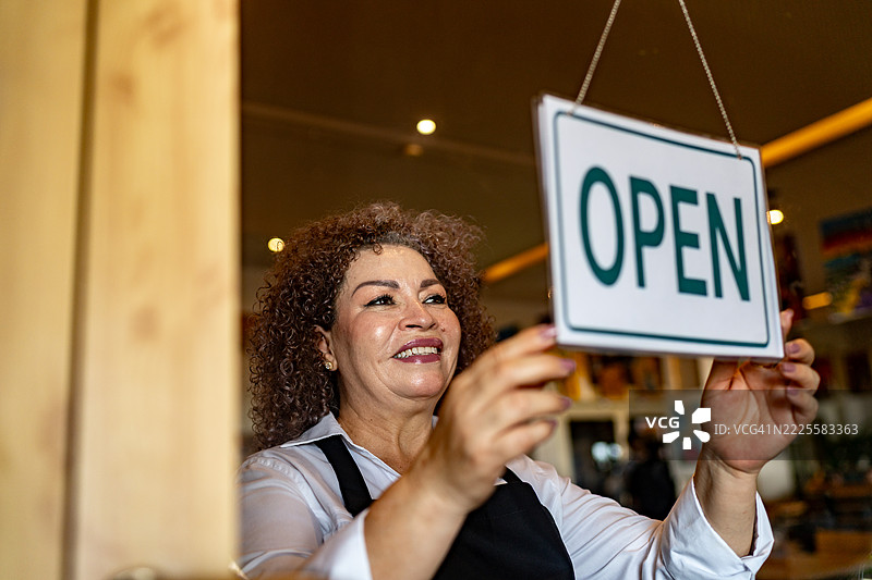 高级女服务员在咖啡店将关闭标志换成开放标志图片素材