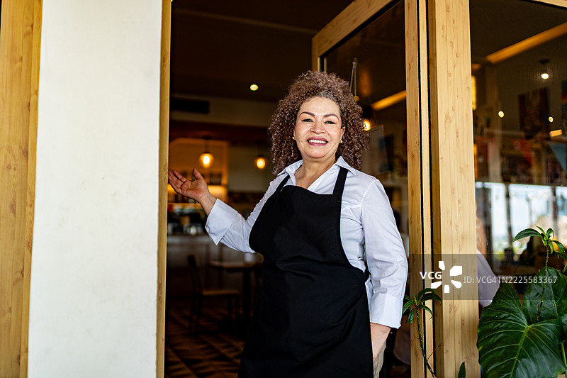 资深女服务员欢迎顾客来到咖啡店的肖像图片素材