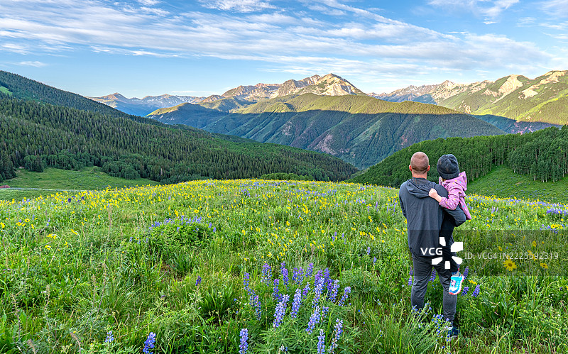 父亲和女儿在美国科罗拉多州中部阿斯彭雪堆村的落基山脉陡坡上，享受夏季野花的清晨时光。图片素材