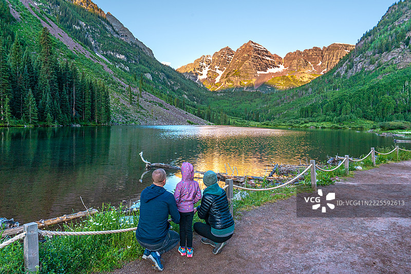 母亲、父亲和女儿在美国科罗拉多州中部的阿斯彭雪堆村地区欣赏著名的栗色钟山和夏季野花，背景是壮丽的落基山脉。图片素材