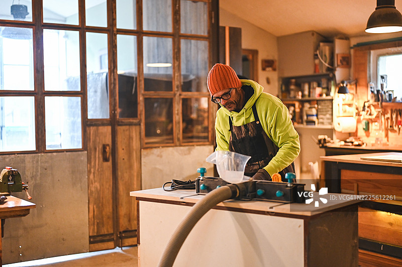 木匠在他的工作坊里将胶水倒入木工机器中图片素材