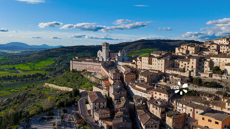 意大利翁布里亚的圣方济各大教堂和圣殿的鸟瞰图，周围是绿色的乡村和历史悠久的城镇建筑，适用于编辑和旅游用途的宗教遗产和旅游素材。图片素材