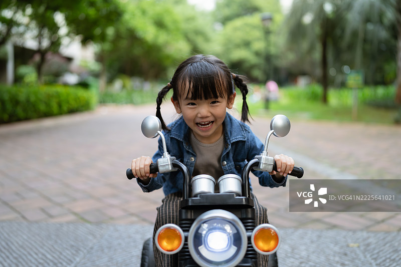 快乐的女孩在公园骑摩托车，充满活力和愉快的氛围图片素材