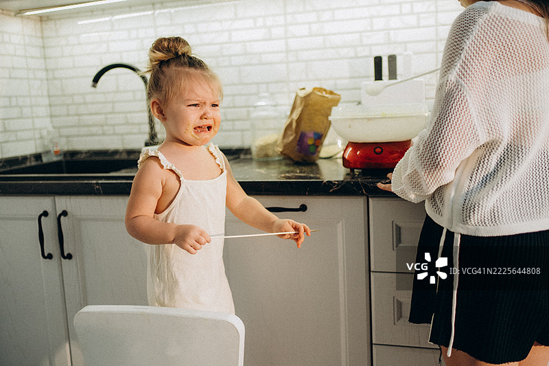 小女孩在厨房里和妈妈一起做棉花糖时哭泣图片素材
