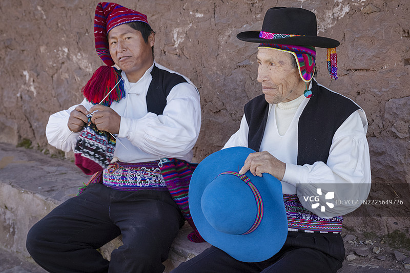在秘鲁塔基莱岛，两名男子正在缝制和编织帽子。图片素材