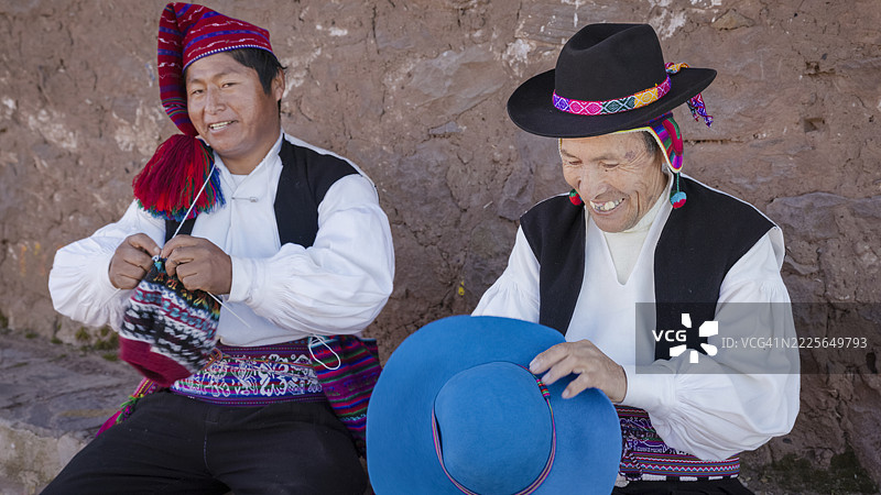 在秘鲁塔基莱岛，两名男子正在缝制和编织帽子。图片素材