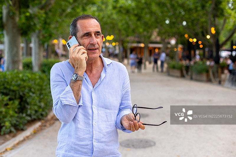 成熟的商人在城市公园里用智能手机通话图片素材
