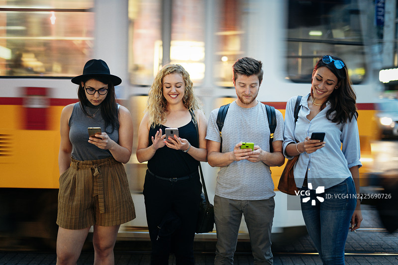 一群年轻人在城市交通中使用智能手机。图片素材