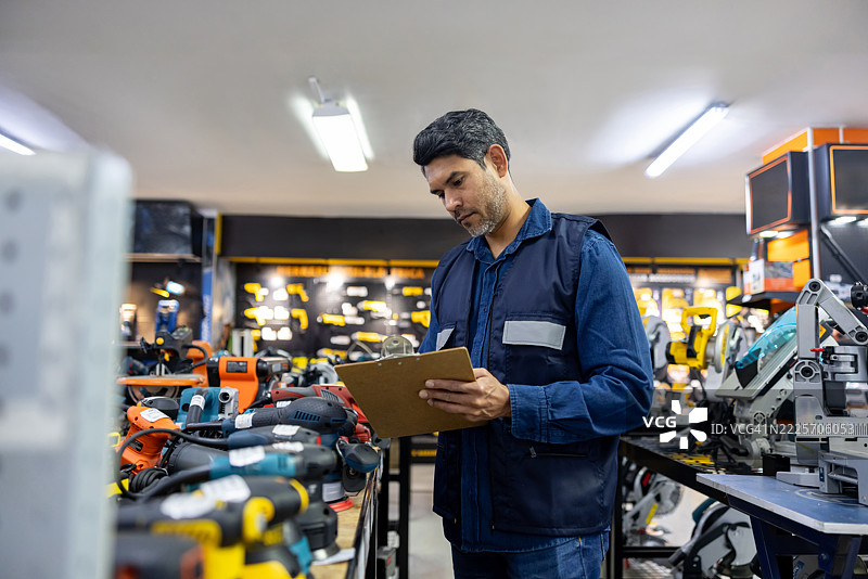 员工在五金店用夹板进行库存盘点图片素材
