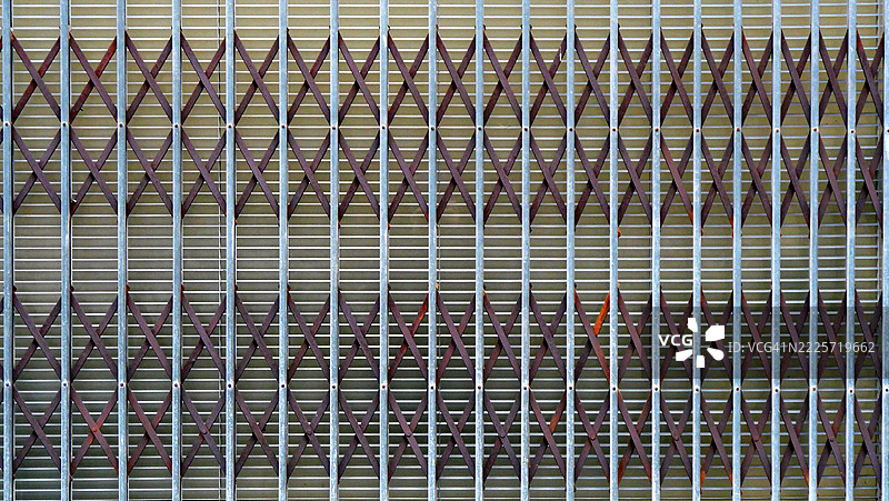 法国巴黎一家商店窗户前的金属折叠式卷帘门,自然色彩和岁月痕迹。阳光。全画幅 16x9。图片素材