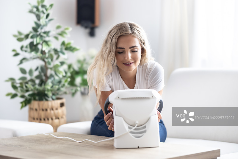 一位年轻女性使用红外灯进行干热疗法，以缓解感冒引起的头痛或肌肉疼痛。图片素材