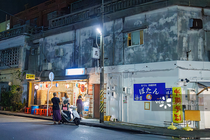 游客进入商店。日本风格酒馆的外观。开放式露台柜台和旧摩托车的展示。图片素材