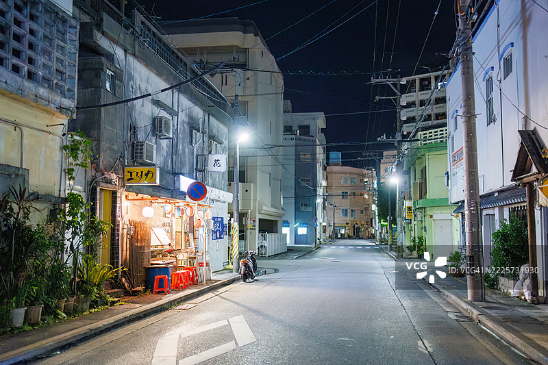 日本风格酒馆的外观。开放式露台柜台和旧摩托车的展示。游客们走进店里。偶尔有出租车经过。图片素材