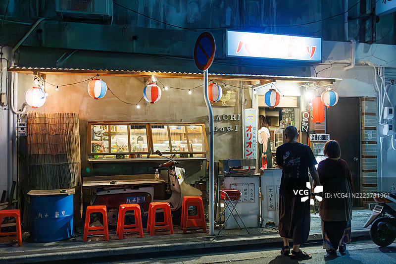 游客进入商店。日本风格酒馆的外观。开放式露台柜台和旧摩托车的展示。图片素材