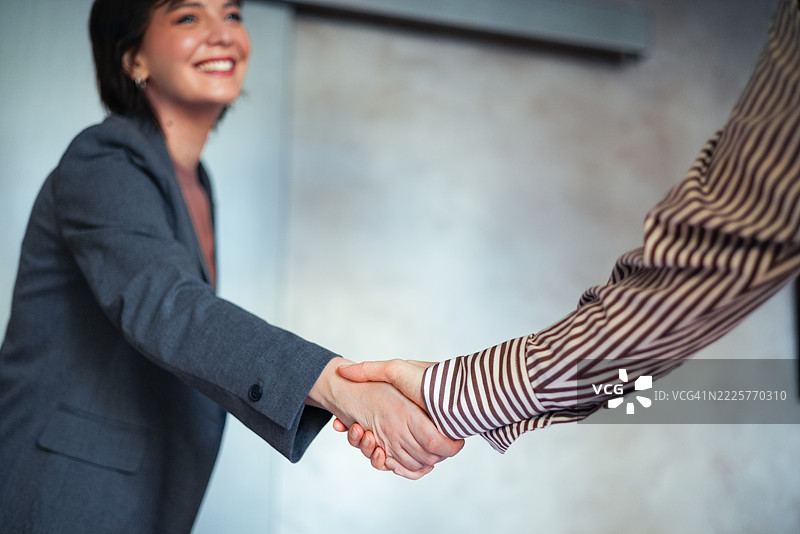 女商人与同事在企业办公室环境中握手图片素材