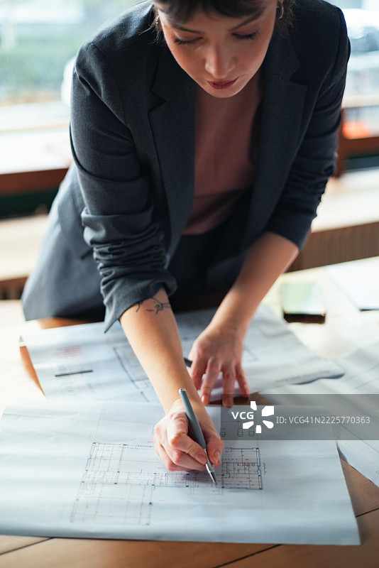 建筑师在工作站专注于项目规划，审查蓝图图片素材