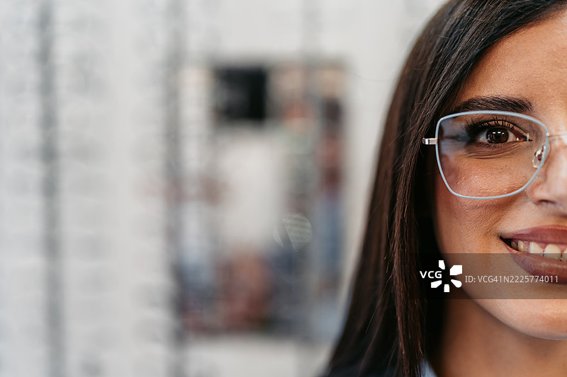在眼镜店里佩戴新眼镜的年轻女性肖像图片素材