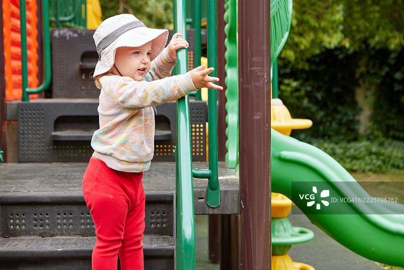 小女孩在游乐场的滑梯上爬台阶图片素材