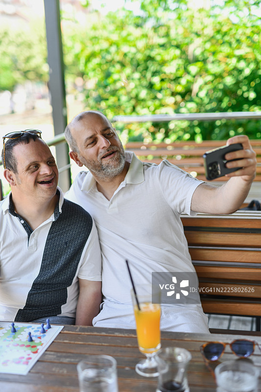 微笑的男孩和有唐氏综合症的兄弟在户外快乐时刻拍摄自拍照图片素材