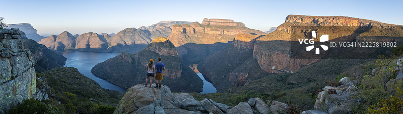 两位徒步旅行者正在欣赏全景,博莱德河峡谷日落,三座隆达韦尔山峰,傍晚时分博莱德河和桌山的峡谷景观,峡谷风光,全景路线,姆普马兰加,南非图片素材