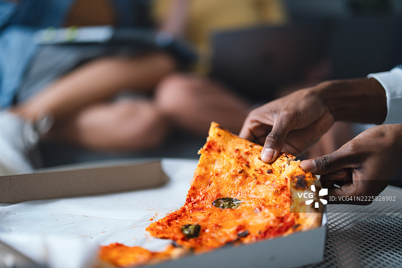 特写镜头：一个人从盒子里拿起一片披萨图片素材