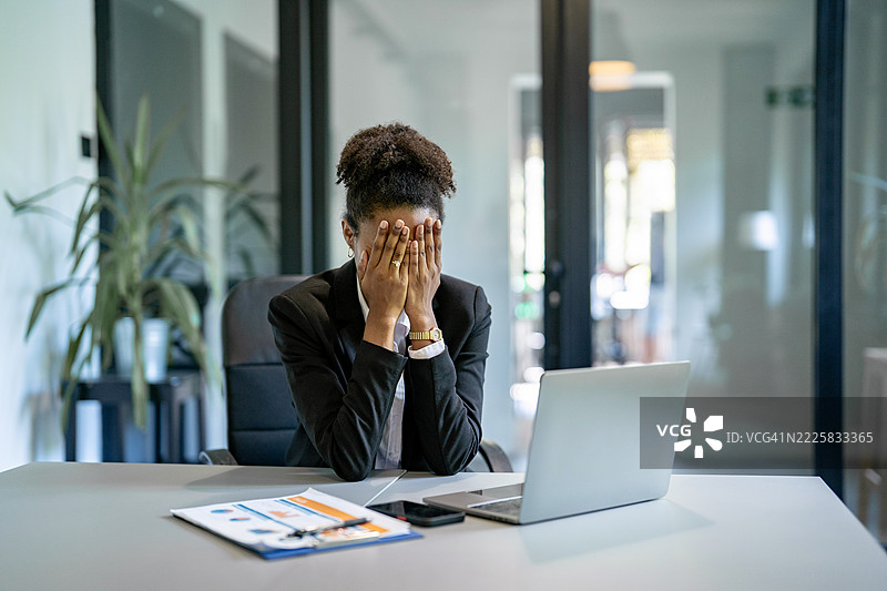 压力大的女商人在办公桌前用双手捂住脸图片素材
