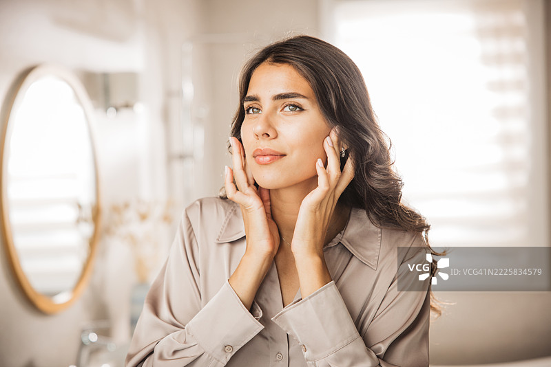 年轻女性面容光滑，正对着镜子凝视图片素材