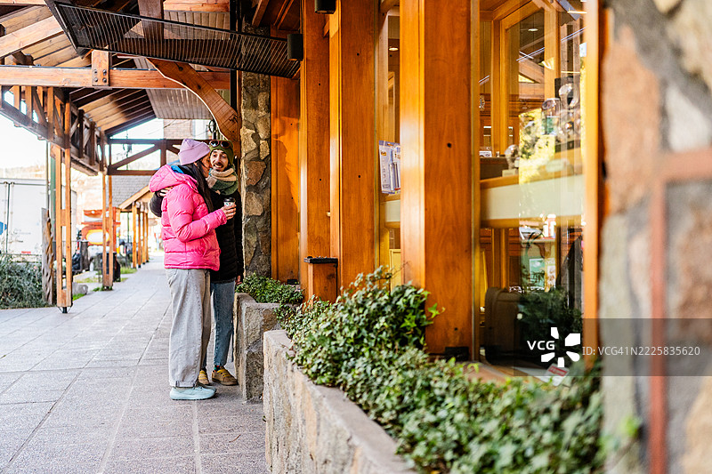 中年夫妇在阿根廷巴塔哥尼亚的圣马丁德洛斯安第斯谈话并观看商店橱窗。图片素材