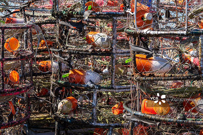 近距离拍摄码头上堆叠的捕蟹笼，笼内有色彩鲜艳的浮标。图片素材