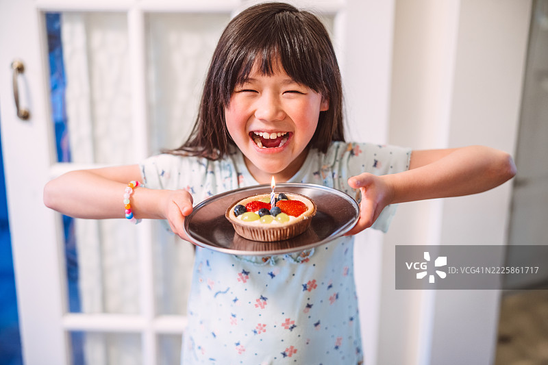 快乐的小女孩在家庆祝生日，享用水果塔。图片素材