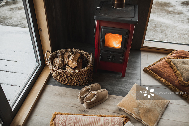 温暖的冬季毛绒靴子靠近壁炉和装有木柴的藤编篮子图片素材
