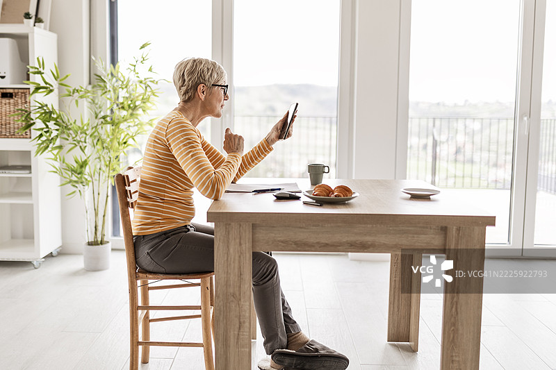 老年女士在厨房桌子上支付账单和制定预算图片素材