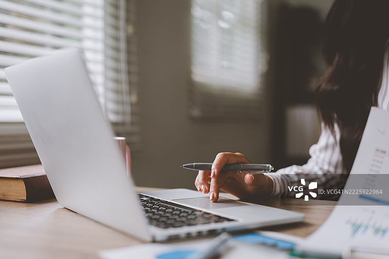 在家工作的女商人使用笔记本电脑分析图表图片素材