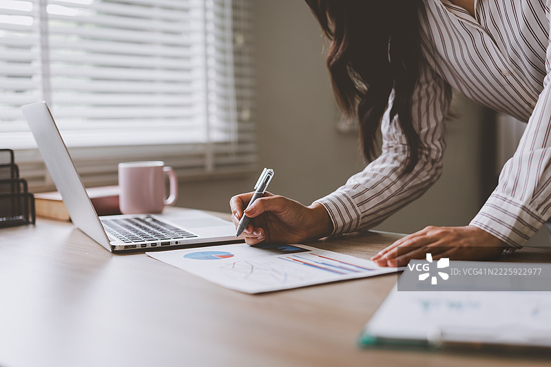 女商人在家办公室分析财务图表并做笔记图片素材