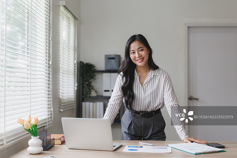 年轻的亚洲女商人在办公室微笑着看向镜头图片素材