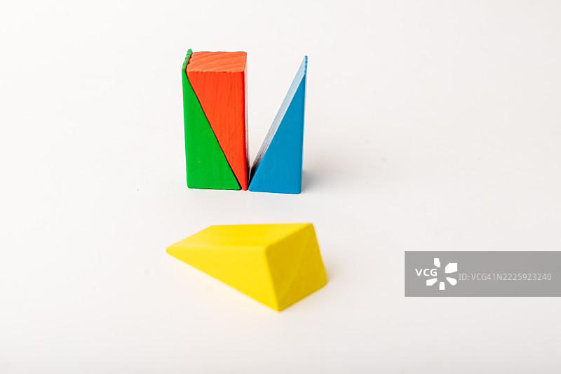 抽象排列的彩色木质几何块，其中一块黄色的单独放置，象征着复杂的游戏。图片素材