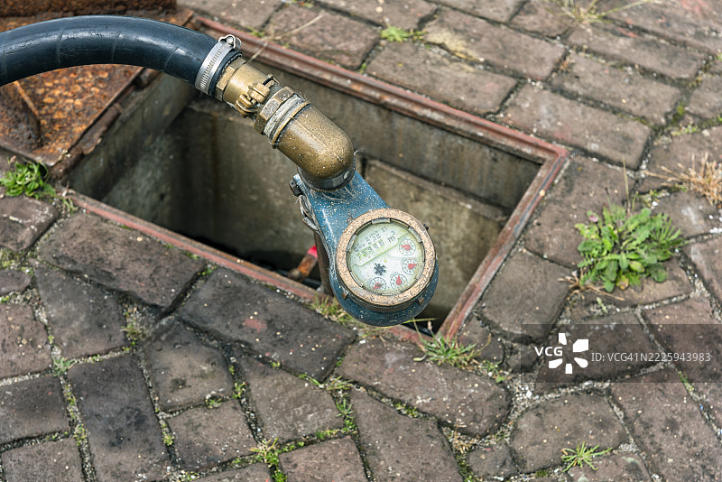 水表特写，连接着黑色橡胶管图片素材
