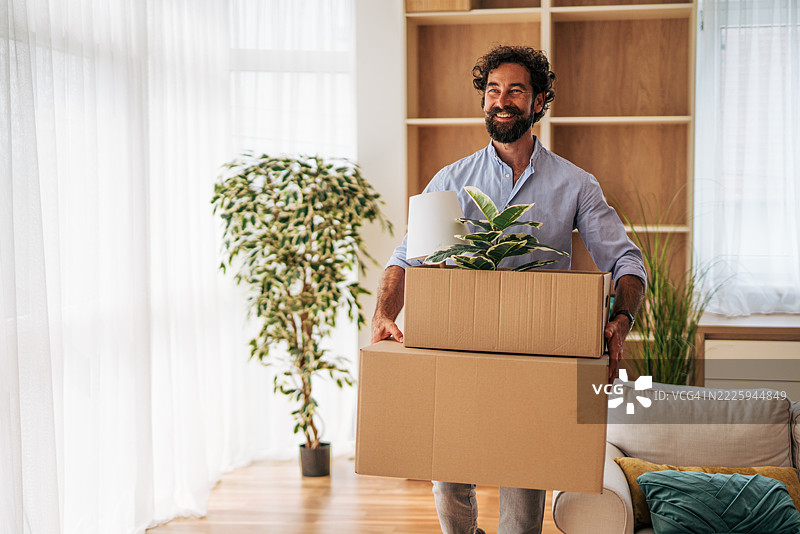 男人将箱子和植物搬入新家图片素材